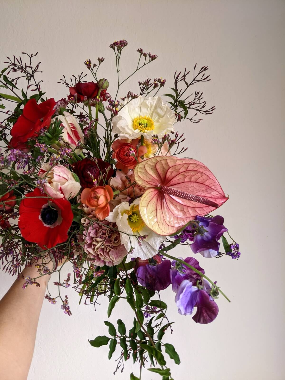 Bouquet of red anemones, white poppies, anthurium, and purple sweet pea