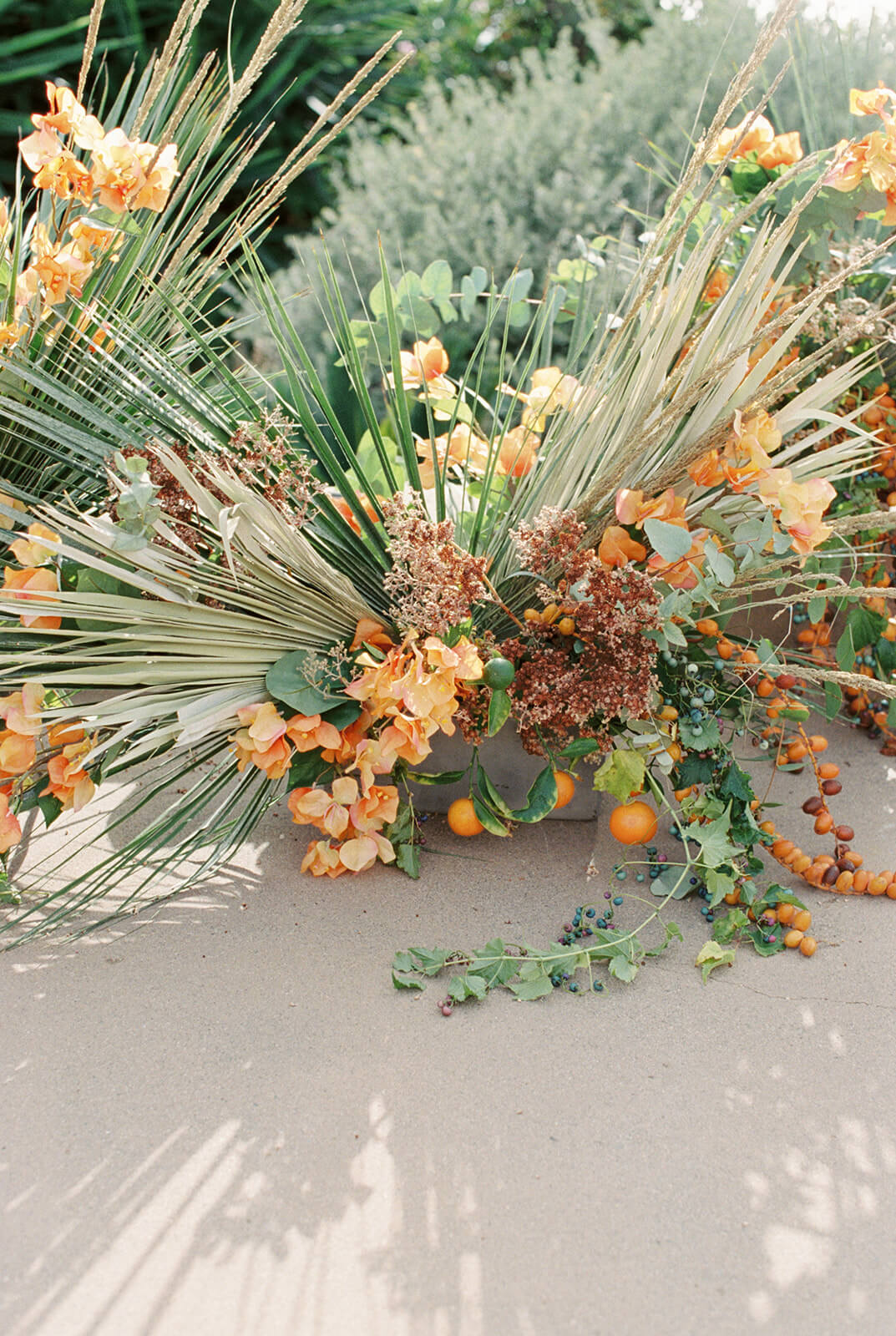Seaside arrangement of grasses, dried hydrangea, and citrus on the sand
