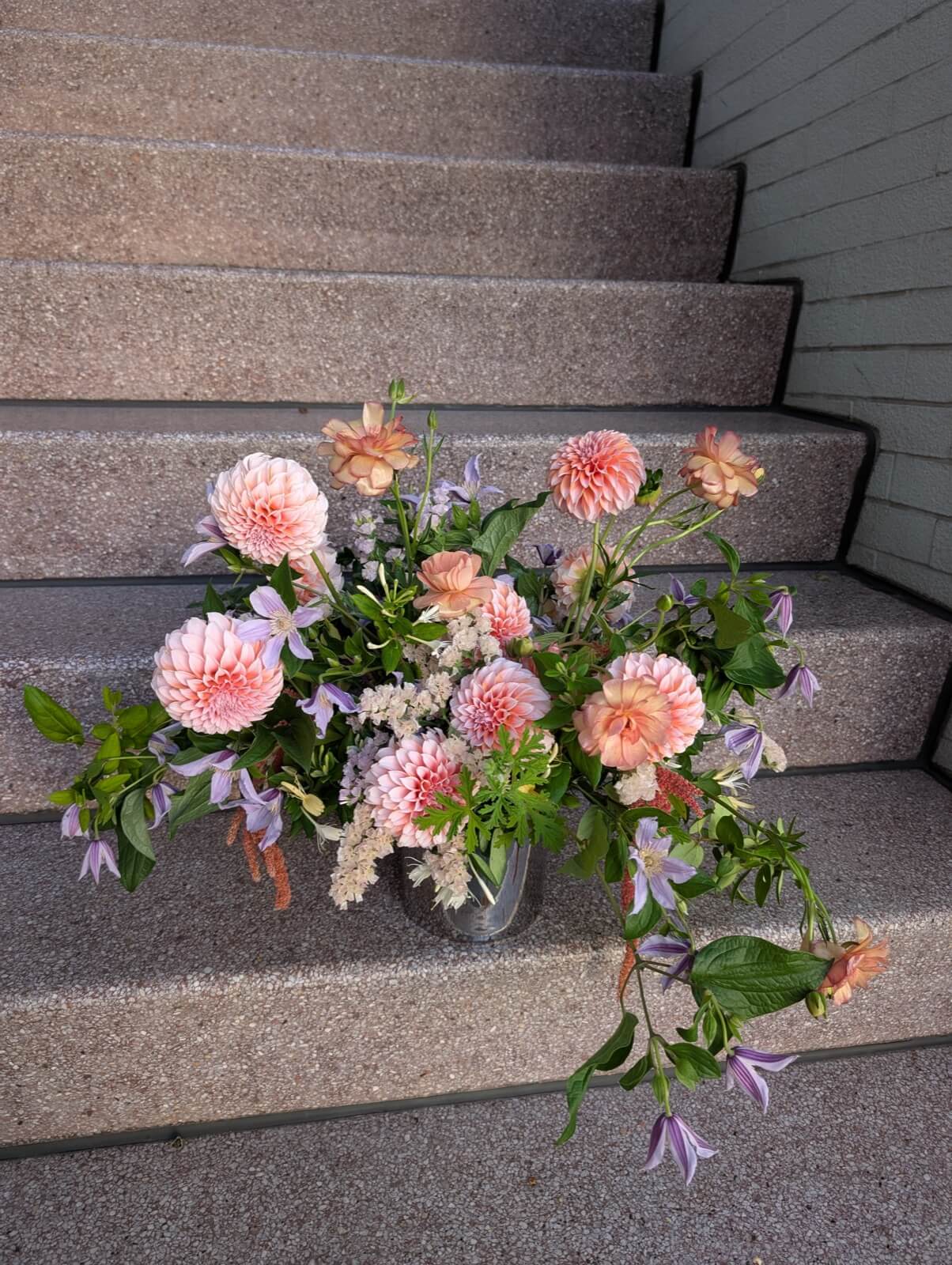 Peach dahlias with clematis and astilbe spilling down concrete steps