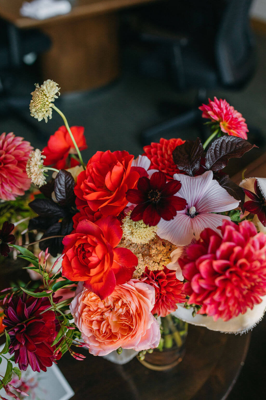 Saturated arrangement of red dahlias, roses, and hibiscus