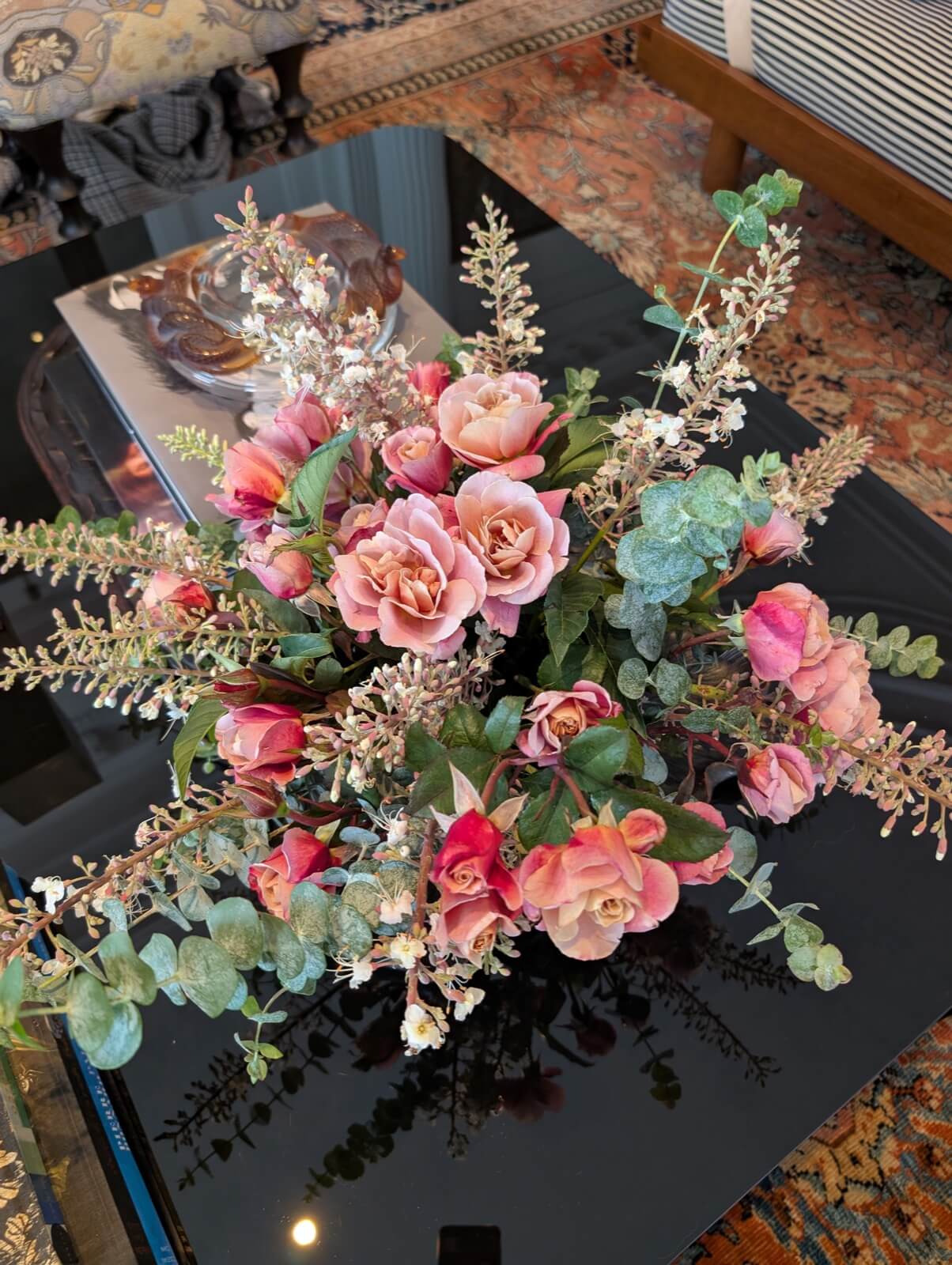 Pink roses and seeded eucalyptus laid across black marble