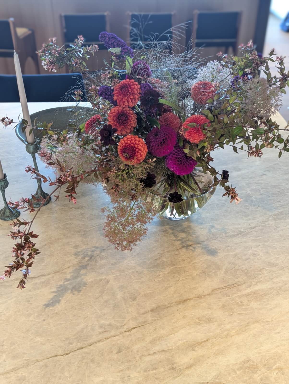 Magenta roses and zinnias with smoke bush in a footed silver compote on a travertine table